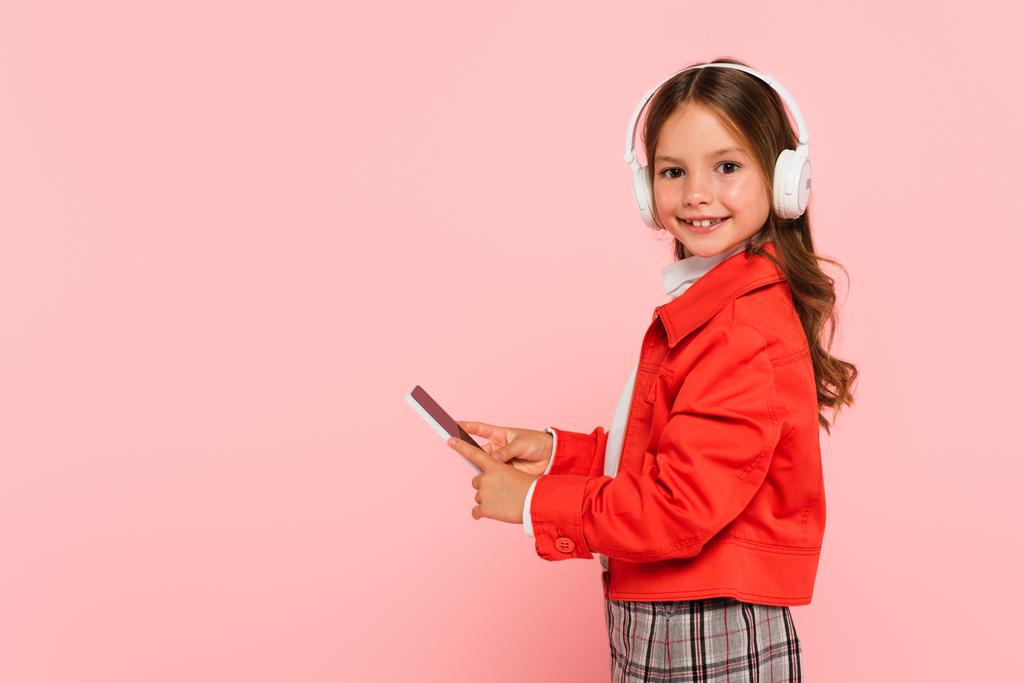 stílusos lány fülhallgató segítségével okostelefon elszigetelt rózsaszín - Fotó, kép