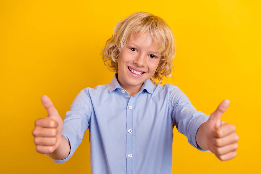 Фото милого маленького хлопчика показують великий палець у синій сорочці ізольовані на жовтому кольорі
 - Фото, зображення
