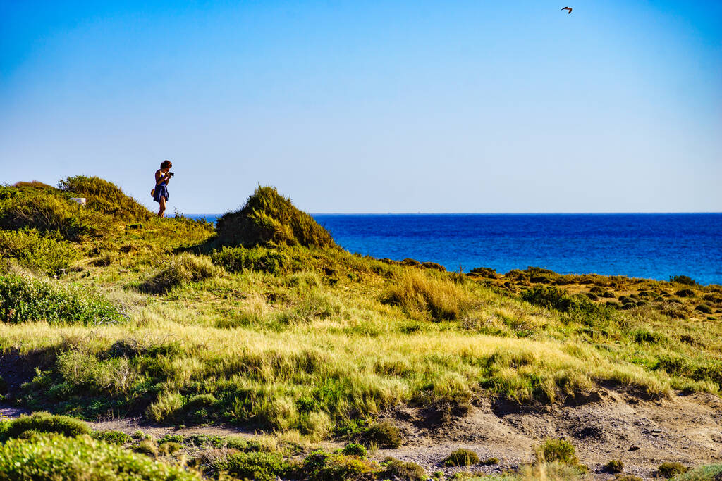Туристична жінка, що йде на березі моря з камерою, фотографує подорожі з морського ландшафту. Парк у Мурсії (Іспанія).. - Фото, зображення