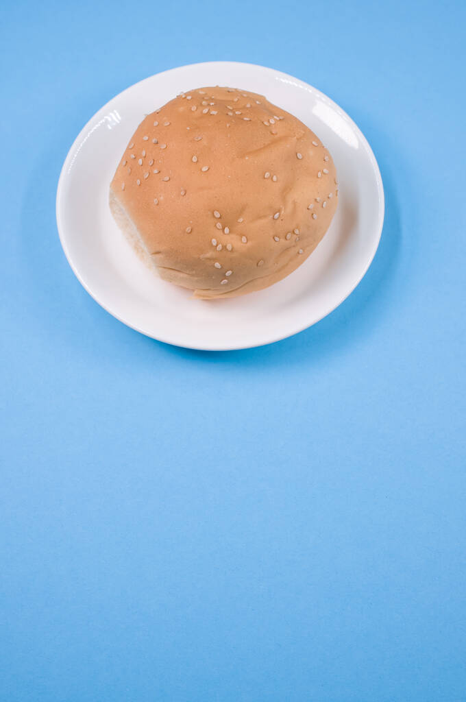 Una toma vertical de pan en un plato aislado sobre fondo azul - Foto, imagen
