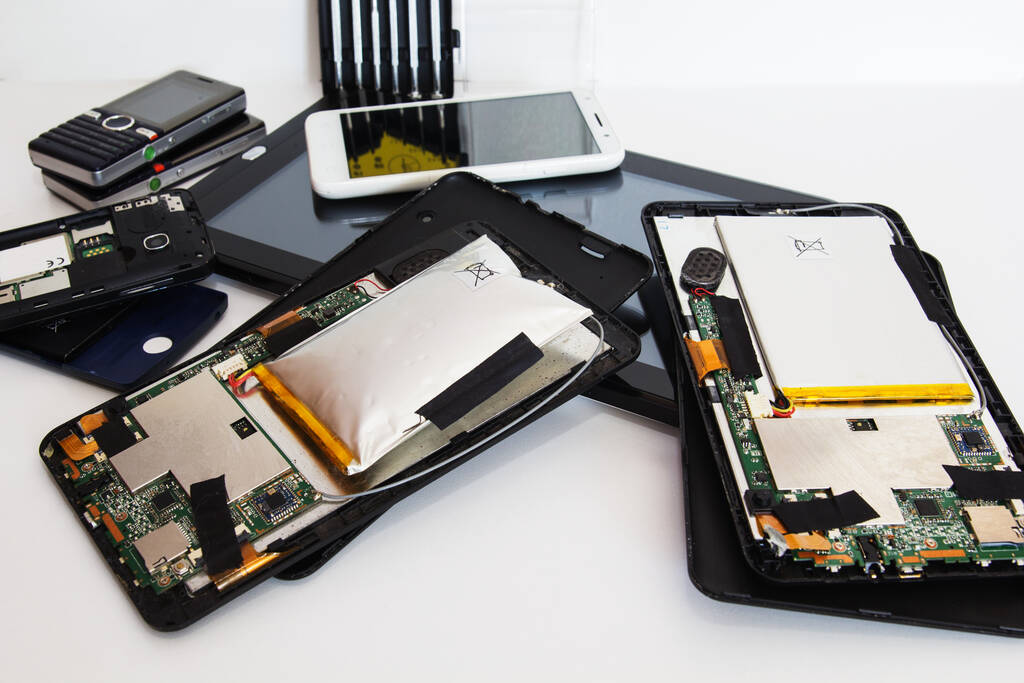 Κατεστραμμένη πρησμένη μπαταρία σε tablet και σπασμένα smartphones.  - Φωτογραφία, εικόνα
