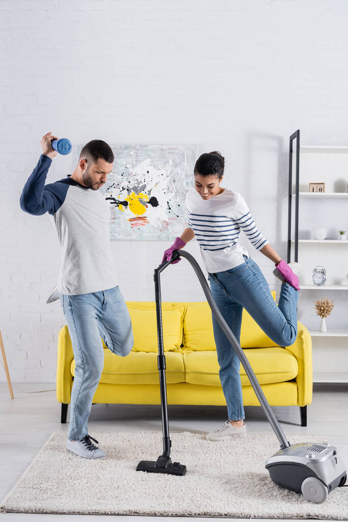 Nuori rotujenvälinen pari tanssia samalla kun puhdistus olohuone  - Valokuva, kuva