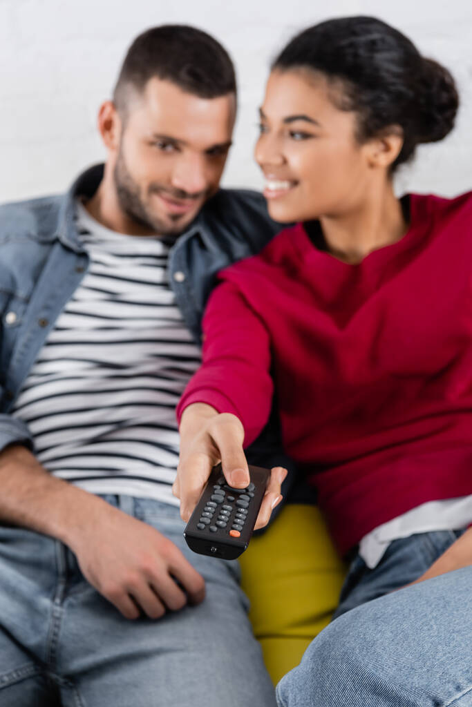 Télécommande en main d'une femme afro-américaine regardant son petit ami  - Photo, image