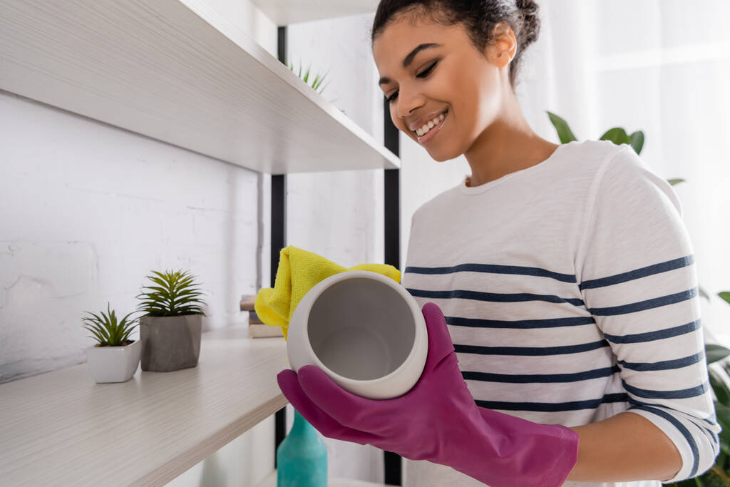 Mosolygó afro-amerikai nő takarítás váza otthon  - Fotó, kép