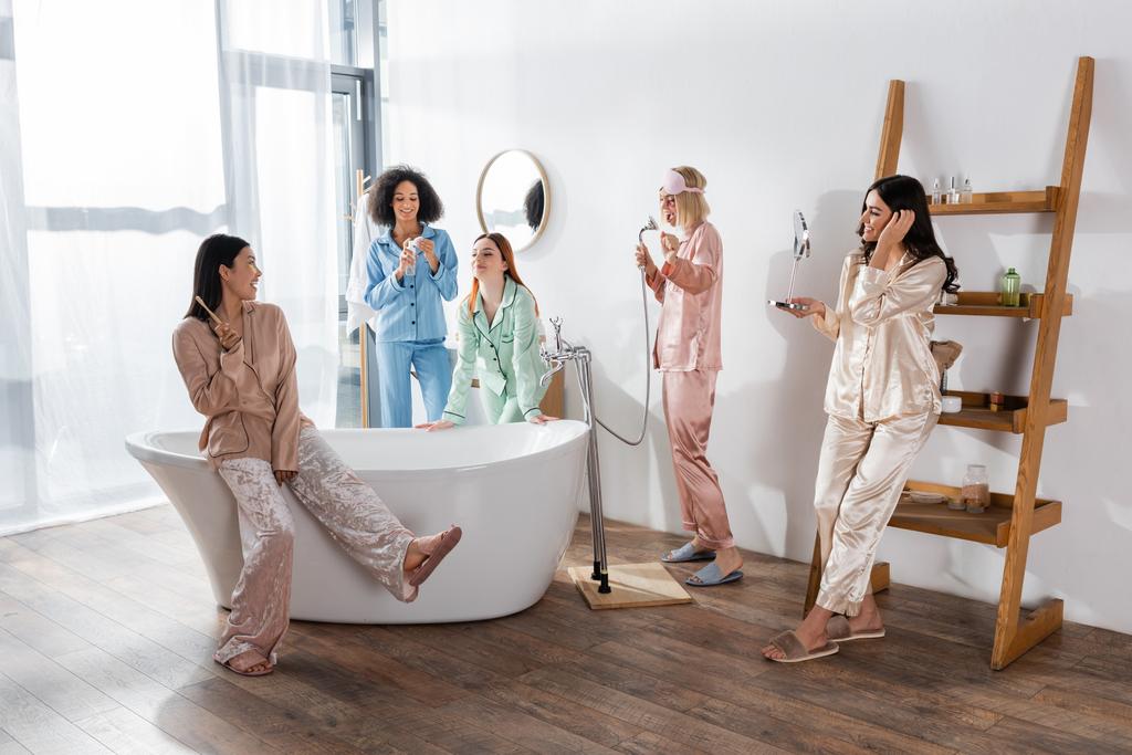 alegres amigos multiétnicos en pijama sonriendo en el baño  - Foto, imagen