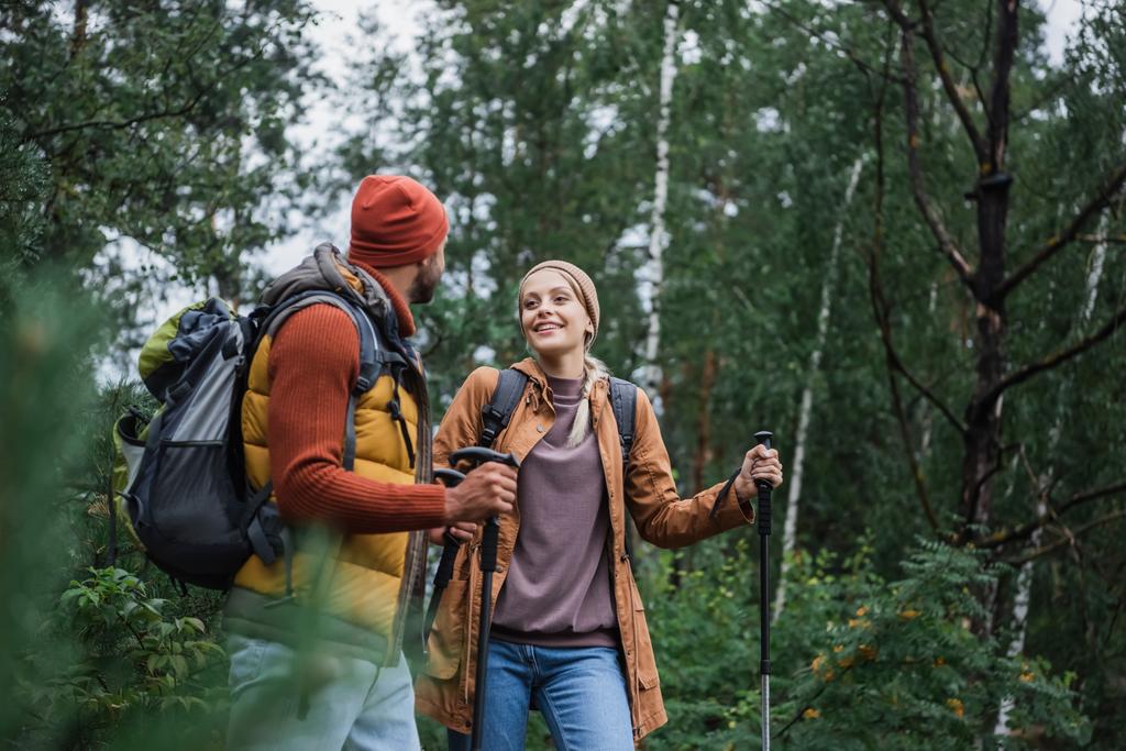 donna felice con bastoni da trekking a piedi e guardando il fidanzato nella foresta  - Foto, immagini