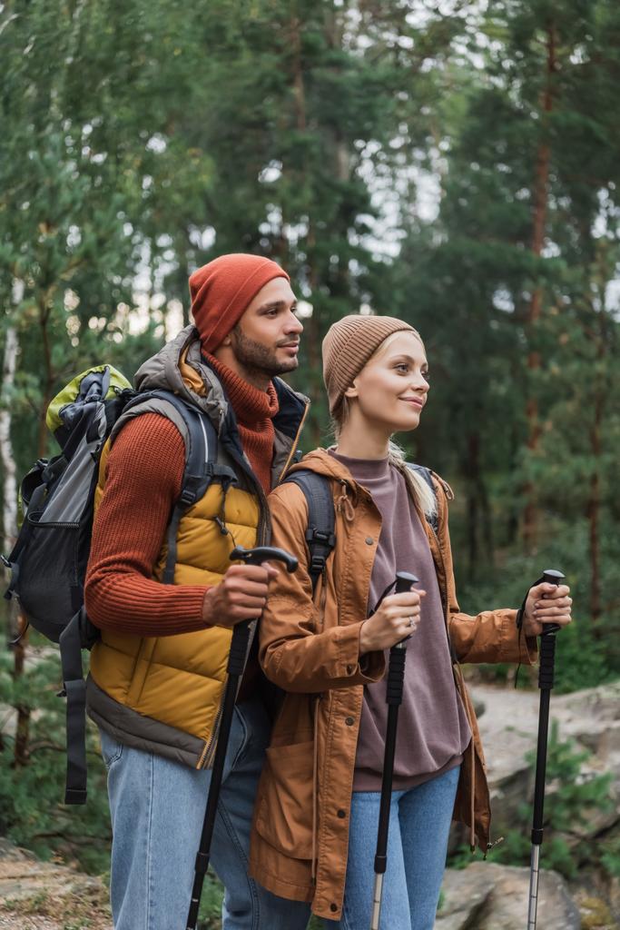 heureux jeune couple avec sacs à dos trekking avec des bâtons de randonnée  - Photo, image