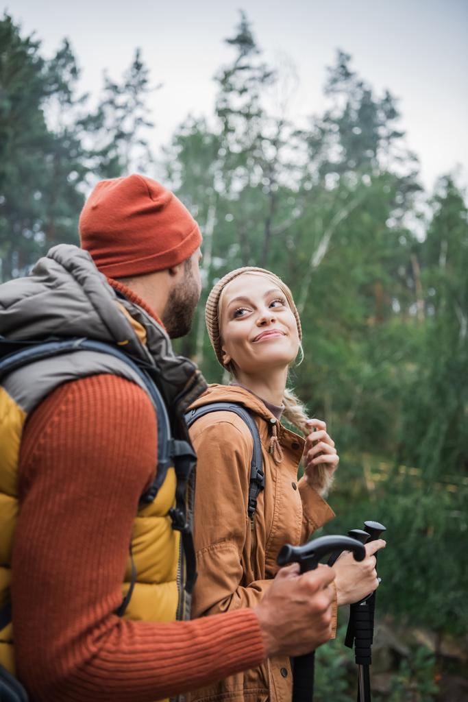 felice giovane coppia con zaini trekking insieme con bastoni da trekking e guardando l'un l'altro  - Foto, immagini