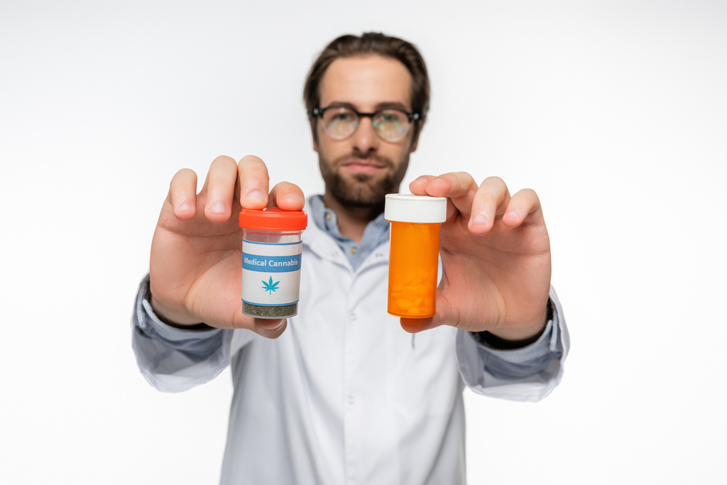 blurred doctor with containers of medication made of medical cannabis isolated on white - Photo, Image