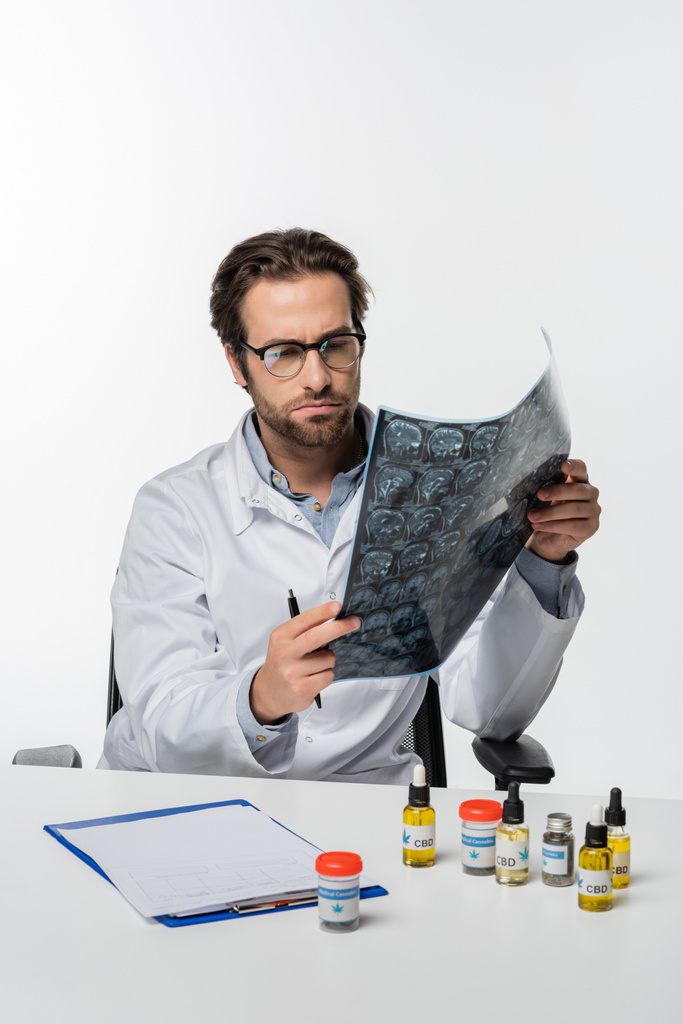 лікар дивиться на сканування мрі поблизу буфера обміну речовин і ліки від конопель ізольовані на білому
 - Фото, зображення