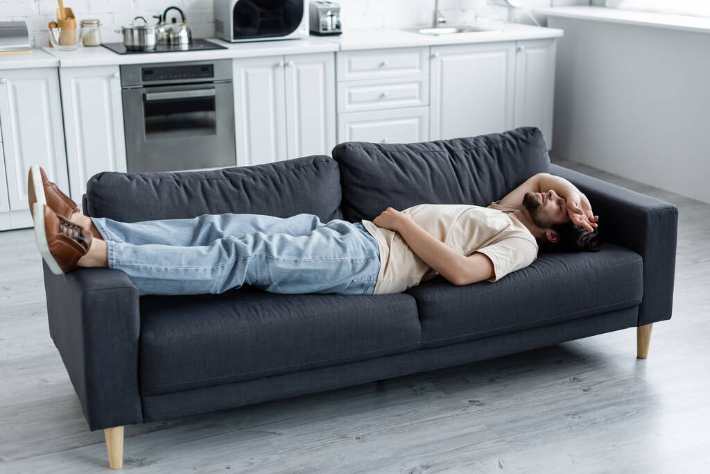 Мужчина, страдающий от боли в животе на диване  - Фото, изображение