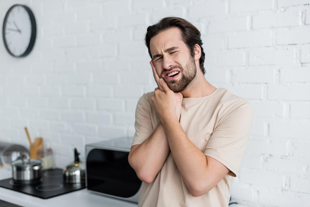 Άνθρωπος που υποφέρει από πονόδοντο ενώ αγγίζει μάγουλο  - Φωτογραφία, εικόνα
