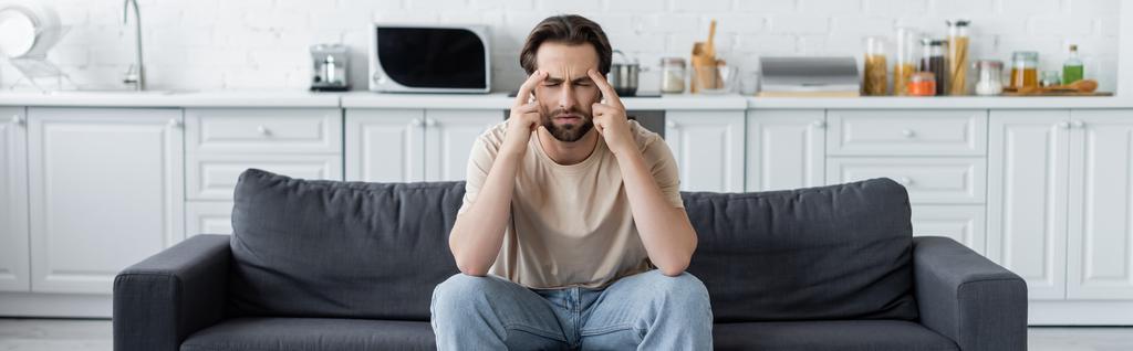 Чоловік, який страждає від головного болю на дивані на кухні, банер
  - Фото, зображення