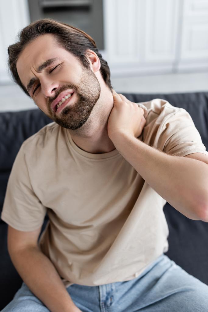 Hombre cansado tocando doloroso cuello en casa  - Foto, imagen