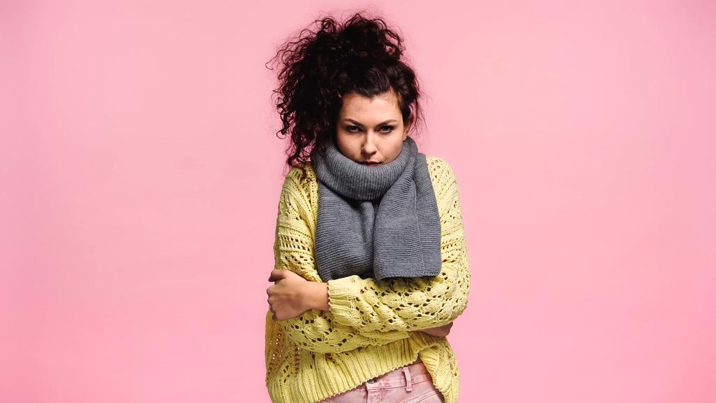displeased woman freezing in sweater and scarf while looking at camera isolated on pink - Photo, Image