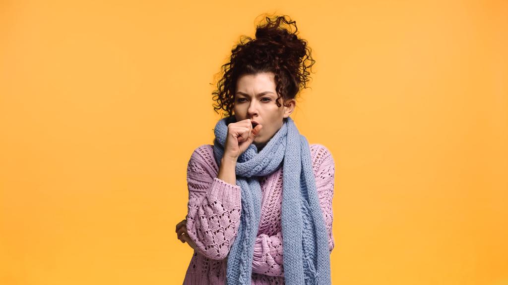 хвора жінка в трикотажному светрі і кашлі шарфа ізольована на апельсині
 - Фото, зображення