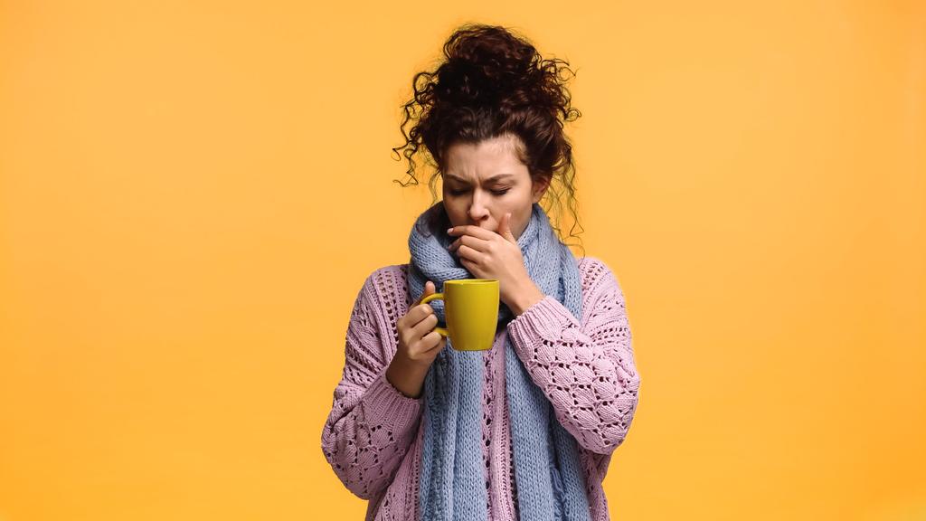 больная женщина с чашкой чая кашель изолированы на оранжевый - Фото, изображение