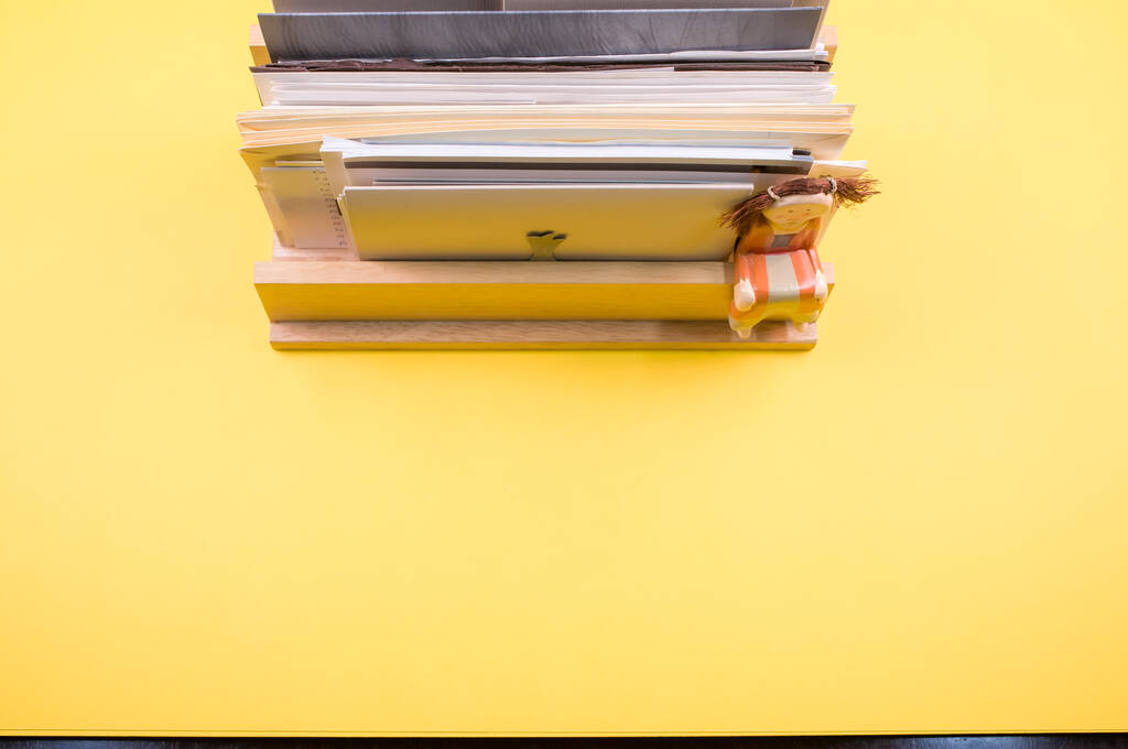 Vista superior de documentos rellenados sobre un estante de madera aislado sobre fondo amarillo - Foto, imagen