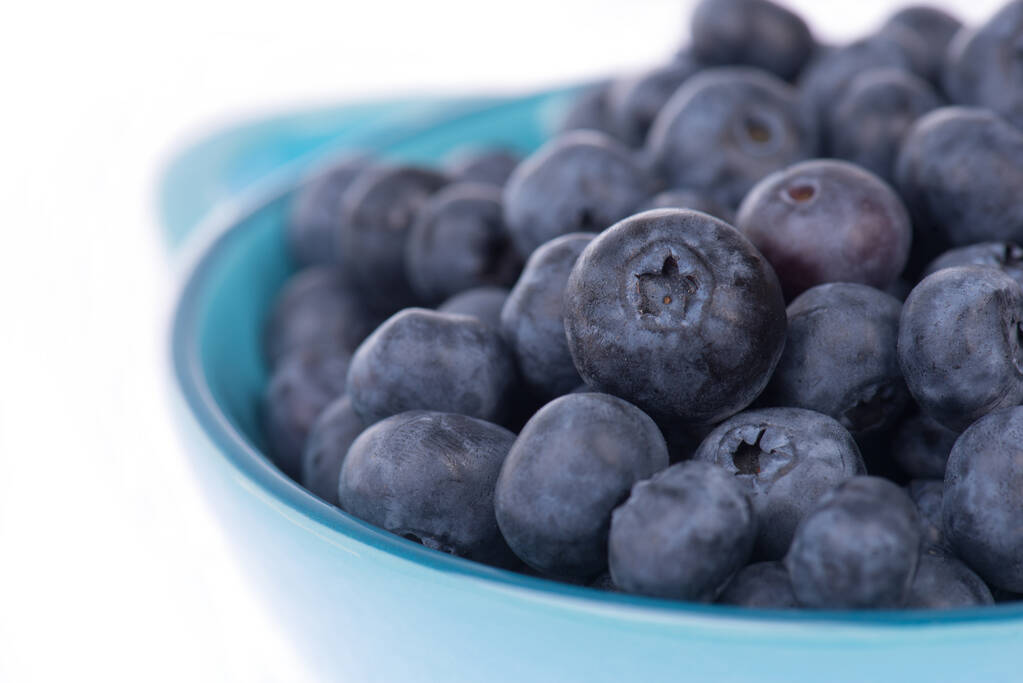 Mirtilli isolati su fondo bianco, frutta fresca in una ciotola blu - Foto, immagini