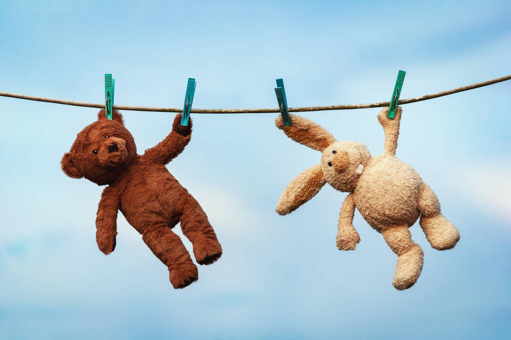 Pluche speelgoed konijn en teddybeer worden gedroogd op een waslijn na het wassen - Foto, afbeelding