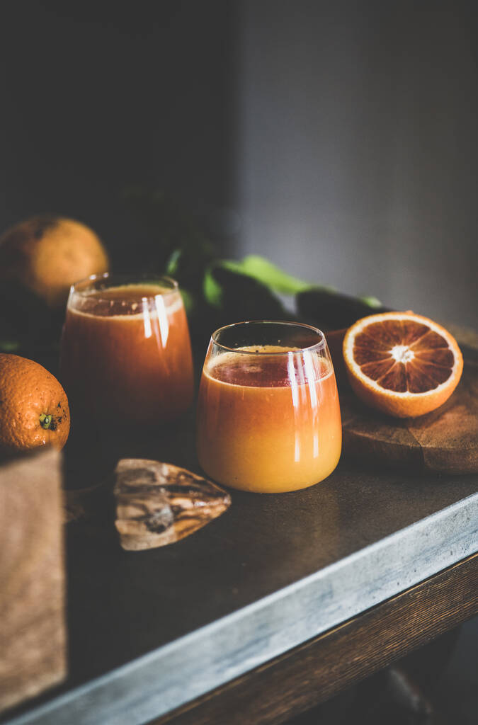 Glasses of freshly squeezed blood orange juice or smoothie on concrete kitchen counter. Healthy lifestyle, vegan, vegetarian, alkaline diet, spring detox concept - Photo, Image