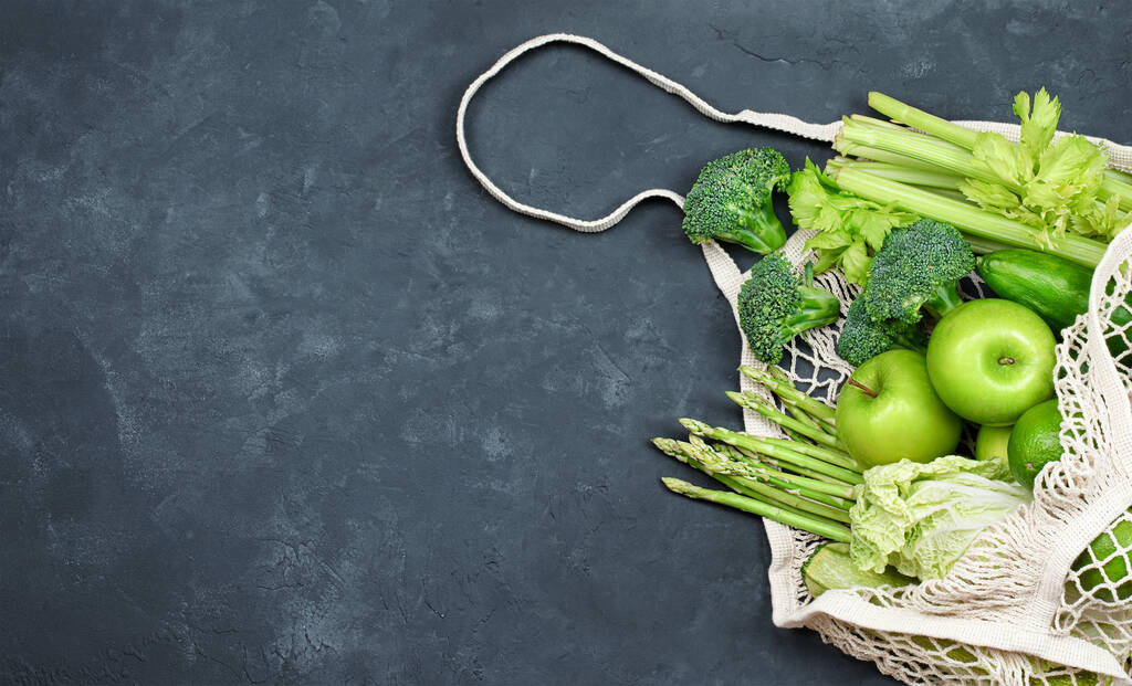 borsa a rete con verdure verdi e frutta su sfondo di cemento nero - Foto, immagini