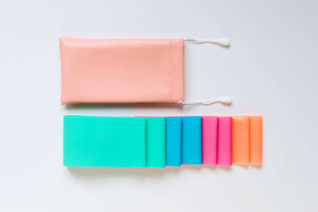 Flat lay of colorful resistance bands with storage pouch on white background.  - Photo, Image