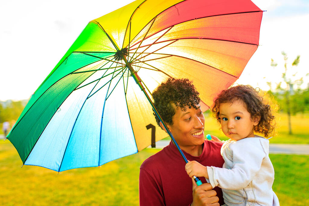 gemengde ras familie dekking van de zon onder de felle paraplu - Foto, afbeelding