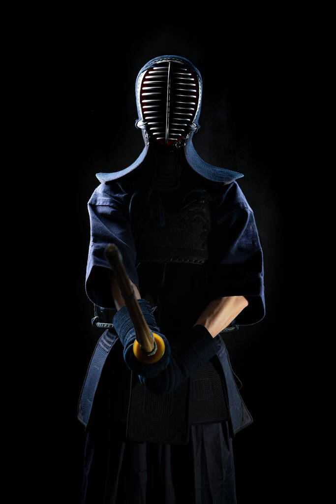 Kendo vechter in volledig uniform op een zwarte achtergrond silhouet. In een masker voor hekwerk. - Foto, afbeelding