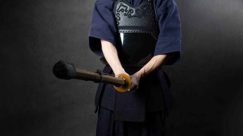 Боєць Кендо в обладунках, практикується з бамбуковим мечем бокуто. Спеціальний бамбуковий меч і спортивна форма. Фото тулуба руками.. - Фото, зображення