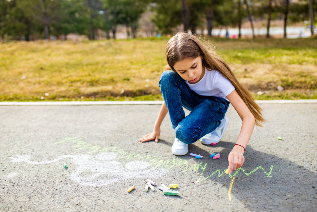 Маленька дівчинка з креативним ременем хобі малює електрони на асфальті з крейдяним автомобілем навколишнього середовища, екологічно чиста, заощаджує енергію в парку в літній день
 - Фото, зображення