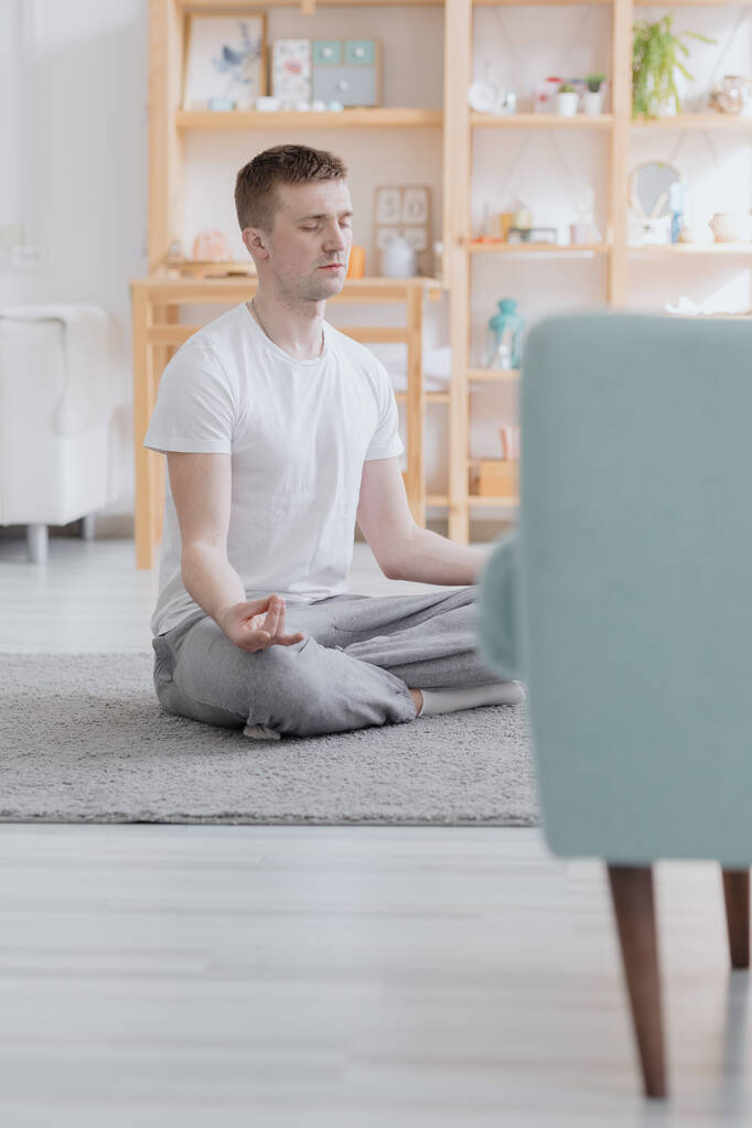 egy európai férfi meditál tágas és hangulatos lakásában, sportjában vagy jógájában, - Fotó, kép