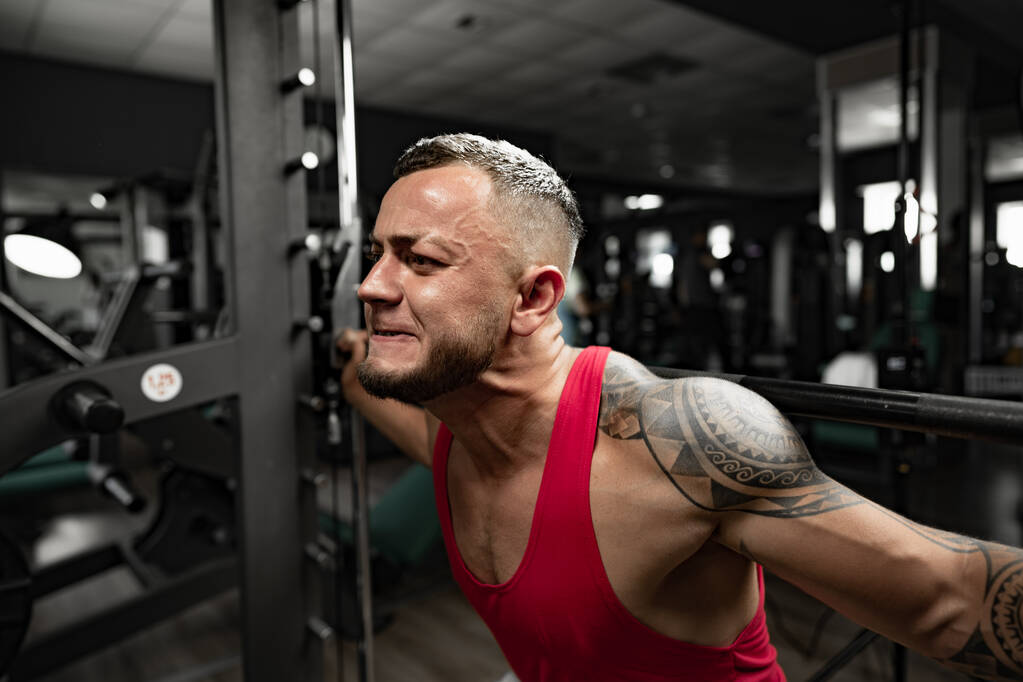 Portrait of man bodybuilder in red shirt in gym - Photo, Image