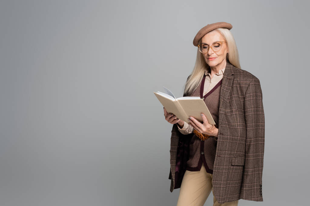 ファッショナブルな女性でジャケットとベレー帽読書本孤立オングレー  - 写真・画像
