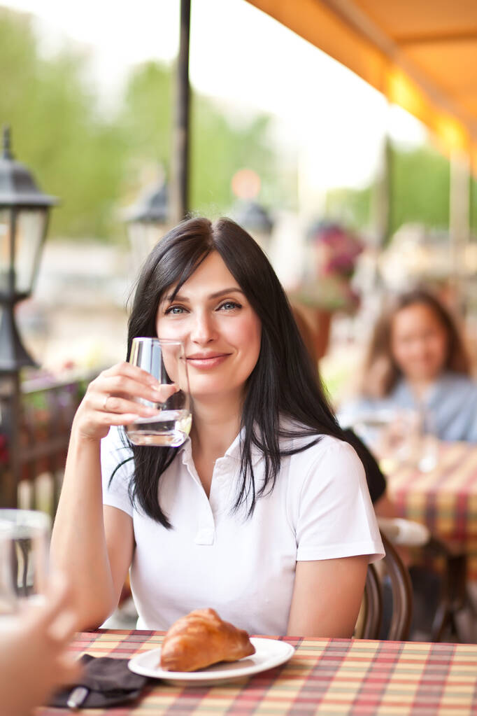 Giovani donne sorridenti al bar a bere vino bianco o acqua. Comunicazione e amicizia concetto. - Foto, immagini