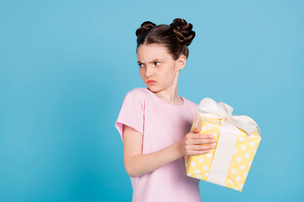 Foto van woedend ongelukkig schoolmeisje dragen roze t-shirt met gele huidige doos op zoek lege ruimte geïsoleerde blauwe kleur achtergrond - Foto, afbeelding