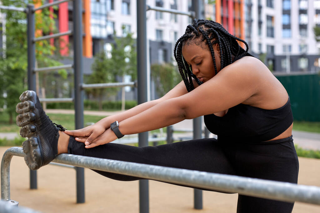 Αφρικανική αμερικανική λίπος γυναίκα τέντωμα πόδια, ζέσταμα πόδια πριν από τη γιόγκα ή προπόνηση αθλητισμού - Φωτογραφία, εικόνα