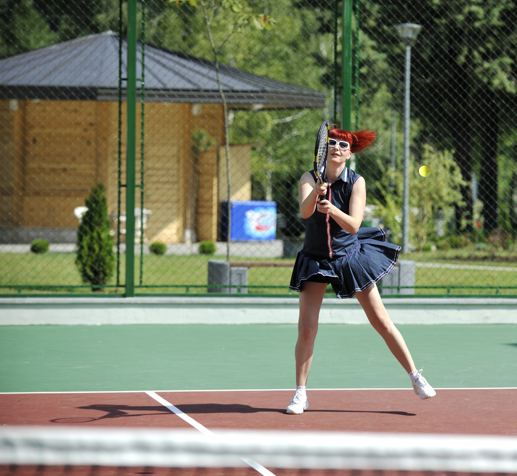 Mujer en forma joven jugar al tenis al aire libre en el campo de tenis naranja en la mañana temprano
 - Foto, imagen