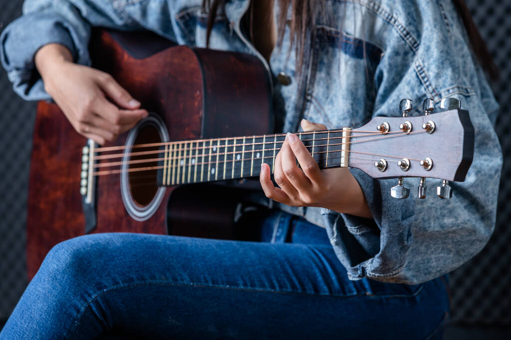 Κοντινό πλάνο γυναίκα δάχτυλα κρατώντας μεσολαβητή με μια κιθάρα ηχογράφηση ενός τραγουδιού στο στούντιο ηχογράφησης - Φωτογραφία, εικόνα