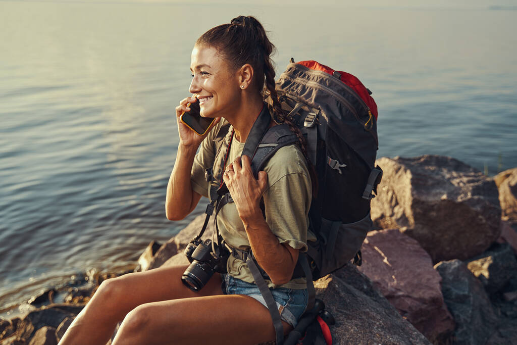 Escursionista parlare al telefono mentre seduto sulla riva del lago - Foto, immagini