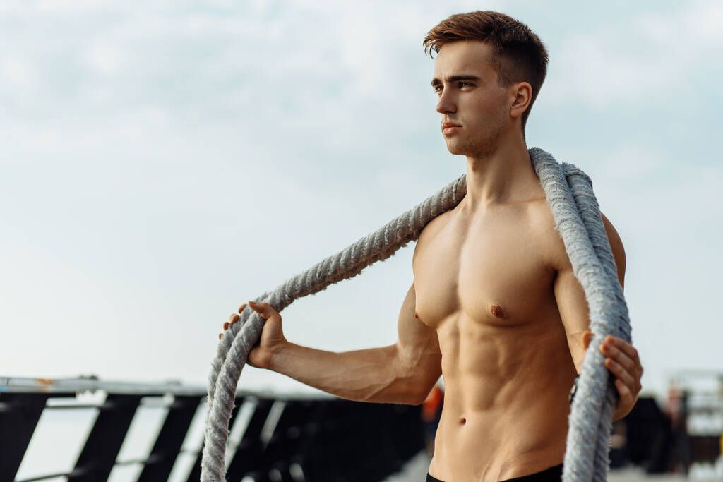Sterke mannentraining met vechttouwen, Sportman die touwtraining buiten op zee doet op de pier, sport, motivatie - Foto, afbeelding