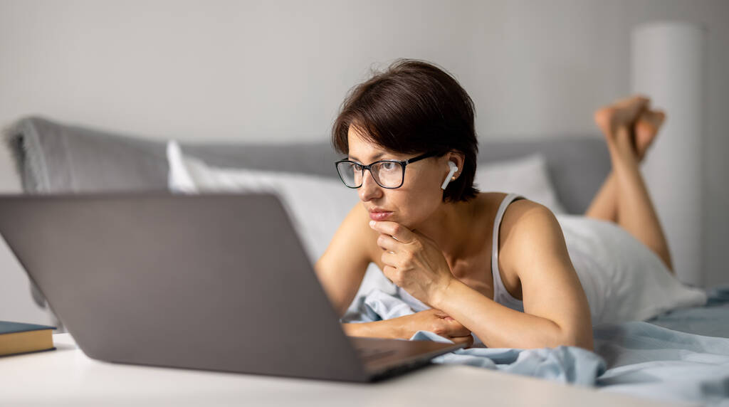 Γυναίκα που χρησιμοποιεί φορητό υπολογιστή στο κρεβάτι - Φωτογραφία, εικόνα