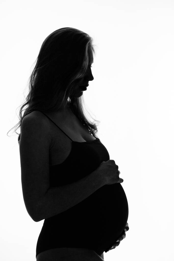 Silueta de mujer embarazada sobre un fondo blanco
 - Foto, imagen