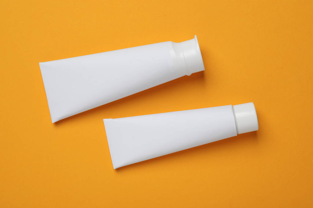 Чистые трубки зубной пасты на оранжевом фоне, плоская укладка - Фото, изображение