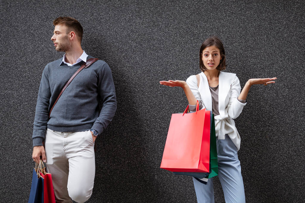 Alışveriş torbaları tutan kadın ve erkek para konusunda anlaşmazlık yaşıyorlar. Tüketim, satış, çift, stres konsepti - Fotoğraf, Görsel