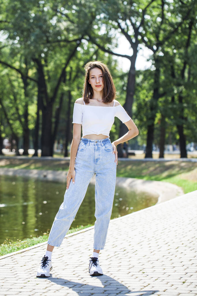 Retrato de comprimento total, jovem menina bonita em jeans azul posando em um parque de verão - Foto, Imagem