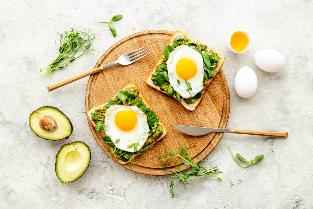Frühstück mit Avocado-Toasts und Spiegeleiern, Blick von oben - Foto, Bild