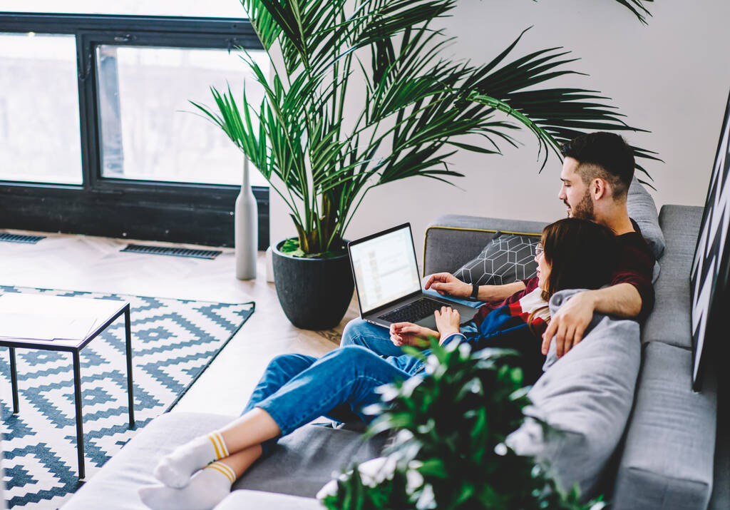 若い結婚は、オンライン配達サービスをチェックソファの上に一緒に横たわっている家に無料の時間に滞在ウェブサイトを参照してください。 - 写真・画像