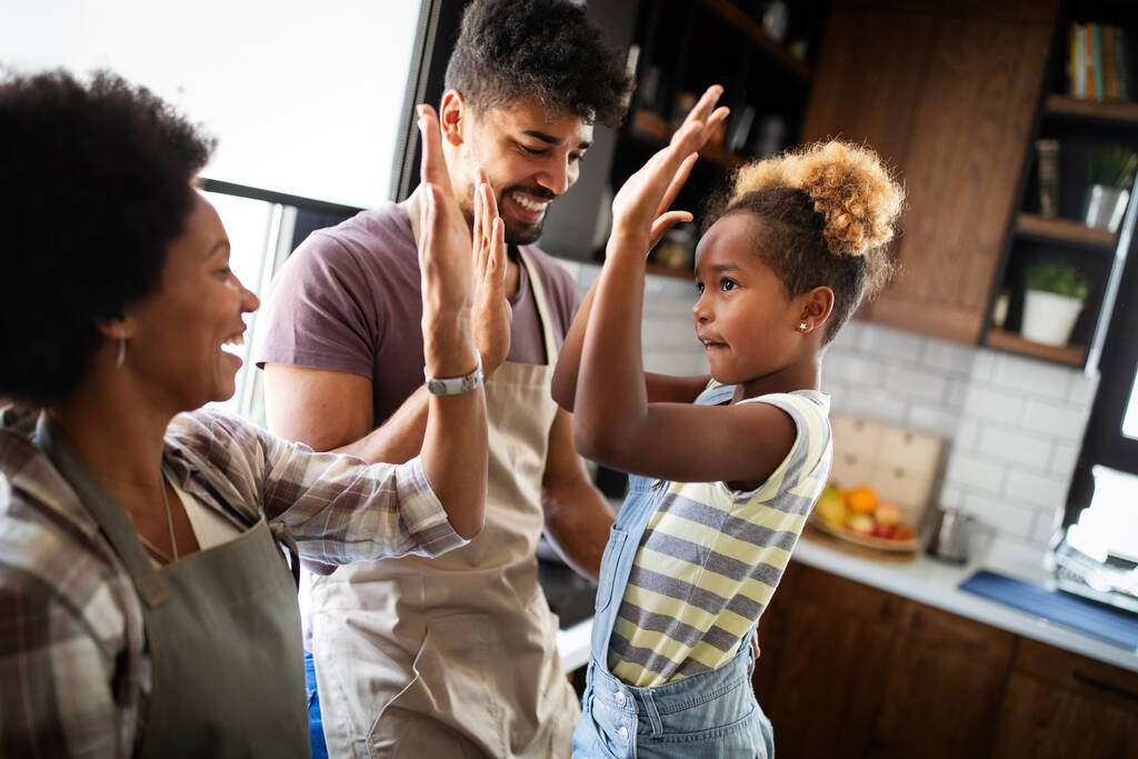 Glückliche Familie bereitet zu Hause in der Küche gemeinsam Essen zu - Foto, Bild