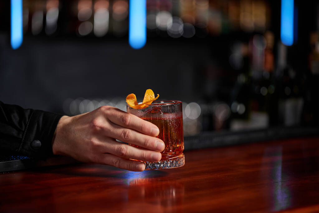 Barmann reicht dem Kunden ein Glas mit alkoholischem Cocktail - Foto, Bild